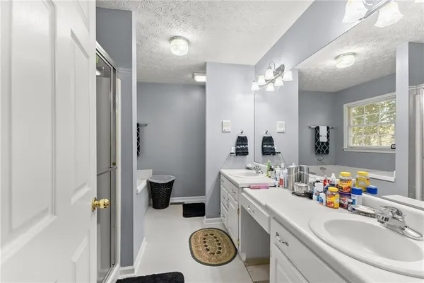 a bathroom with a sink double vanity granite tub shower and a mirror