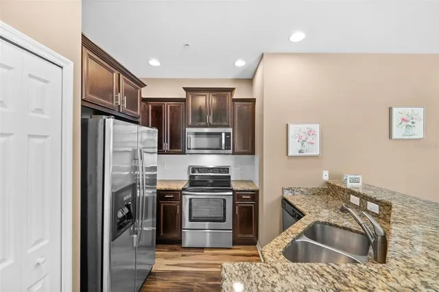 a kitchen with stainless steel appliances granite countertop a refrigerator sink and stove