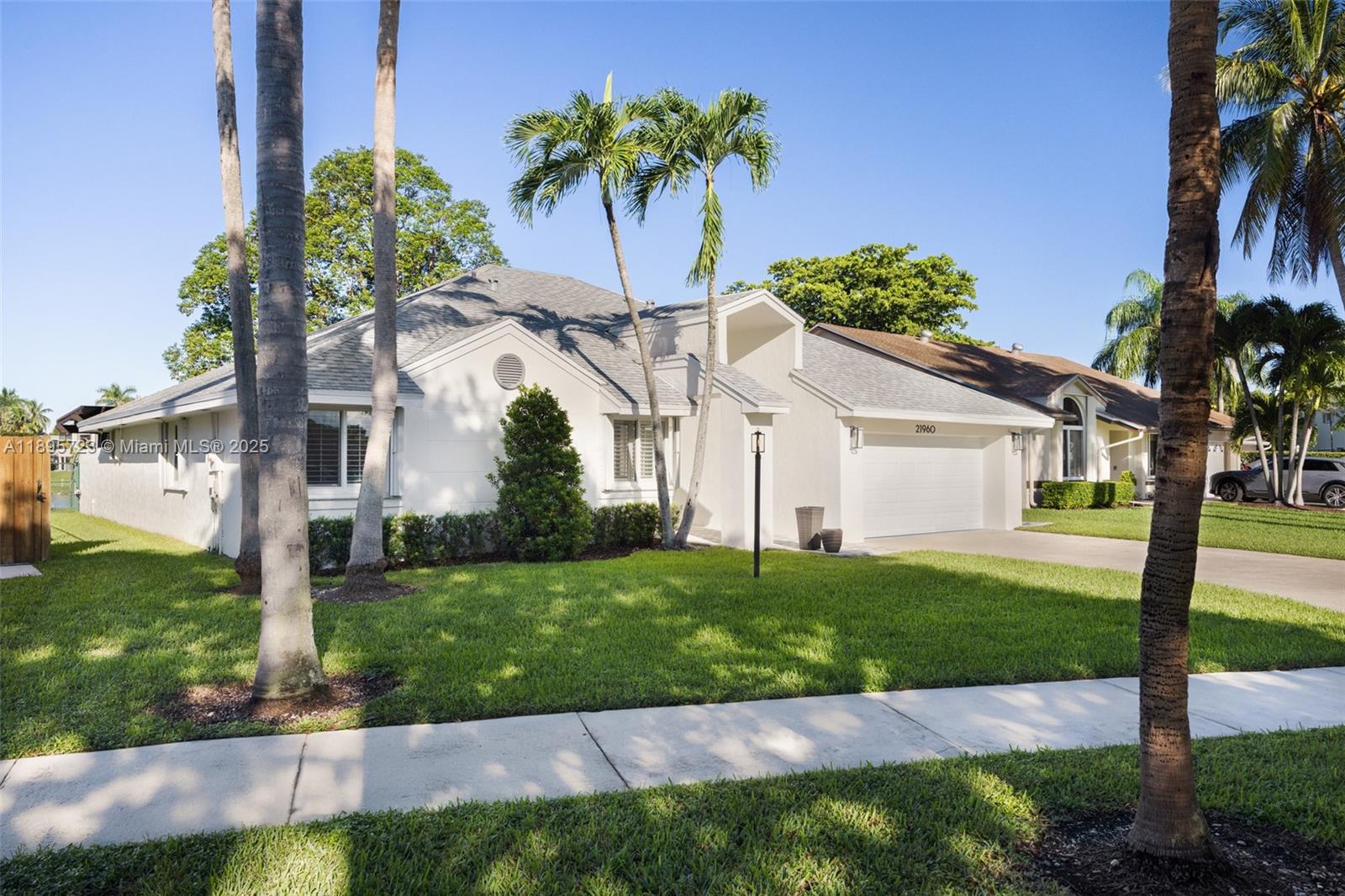 21960 Southwest 98th Avenue Cutler Bay, FL 33190 - Photo 2 of 25 a view of a white house next to a yard with palm trees