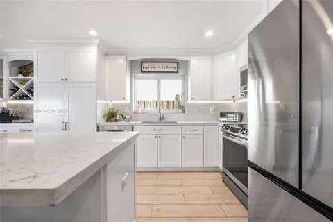 a kitchen with stainless steel appliances granite countertop a refrigerator and a sink
