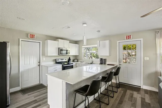 a kitchen with stainless steel appliances a stove a sink a microwave a refrigerator and chairs