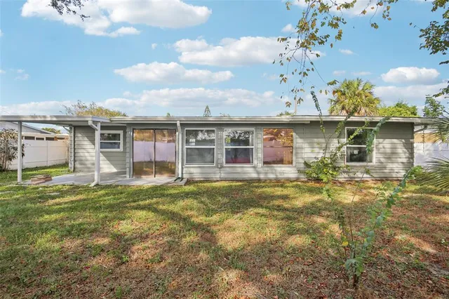 a view of a house with a backyard and a large tree