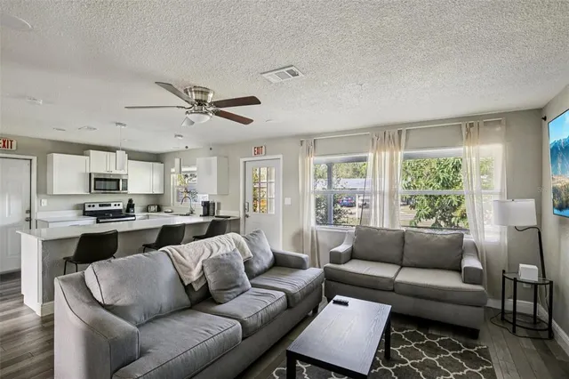 a living room with furniture kitchen view and a large window