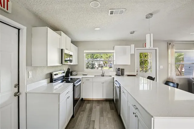 a kitchen with a sink stove cabinets and wooden floor