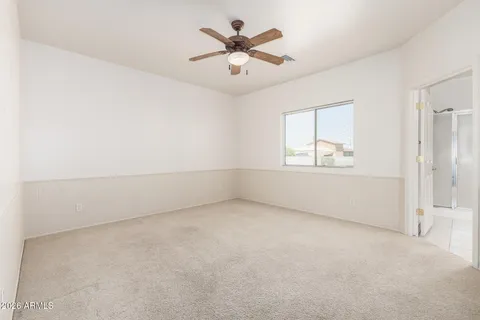 an empty room with chandelier fan and windows