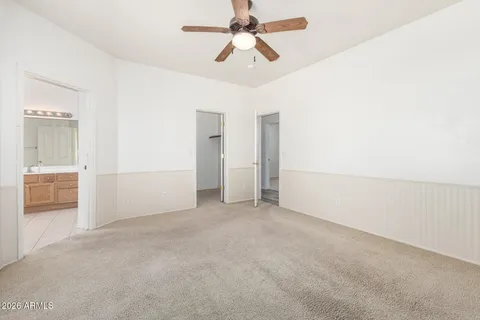 an empty room with chandelier fan and windows
