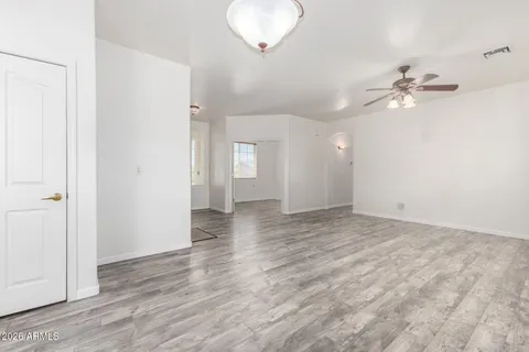 an empty room with wooden floor and ceiling fan