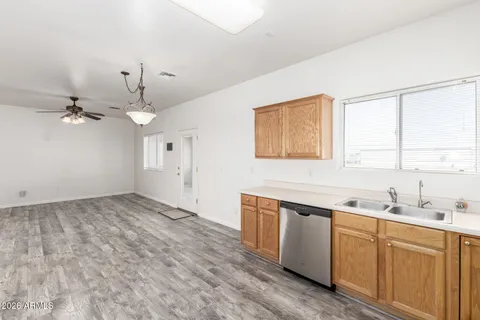 a view of a kitchen with a sink dishwasher large window and wooden floor