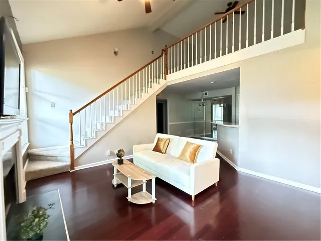 a living room with couches and a dining table with wooden floor