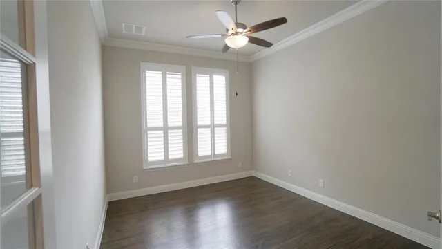 an empty room with wooden floor ceiling fan and windows