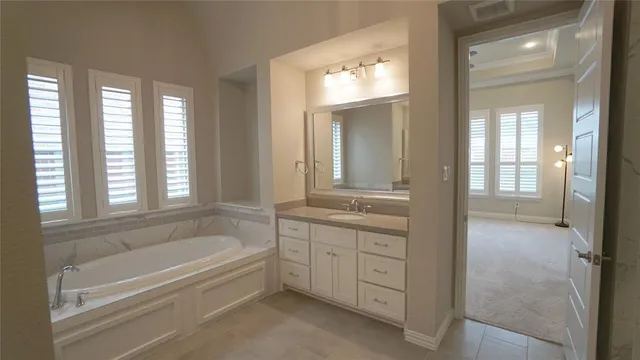 a spacious bathroom with a tub sink and mirror