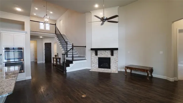 an empty room with wooden floor fireplace and staircase
