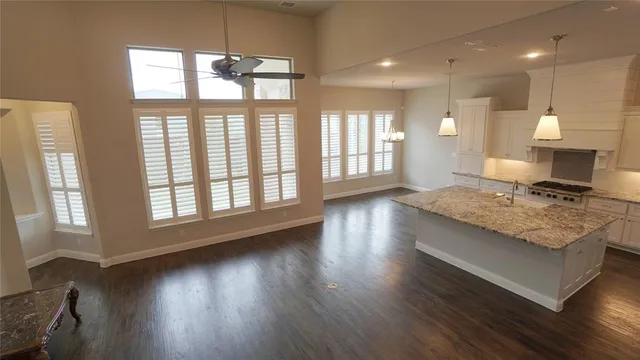 a living room with kitchen island granite countertop wooden floor and a large window