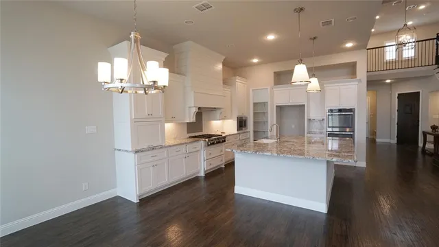 a large kitchen with granite countertop a large counter top stainless steel appliances and cabinets