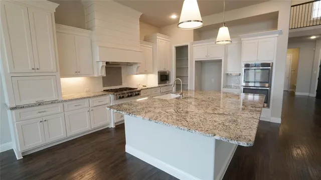a kitchen with kitchen island granite countertop a sink cabinets and stainless steel appliances