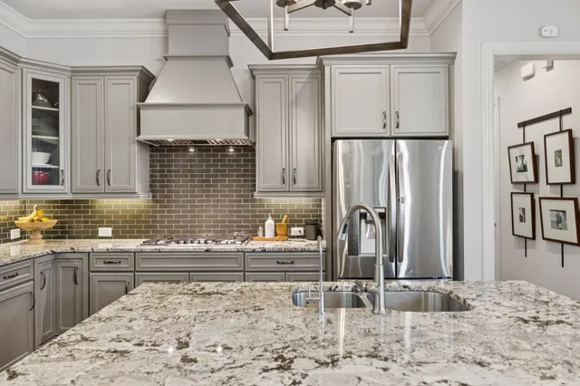 a kitchen with stainless steel appliances granite countertop a refrigerator a stove a sink dishwasher a dining table and chairs with wooden floor