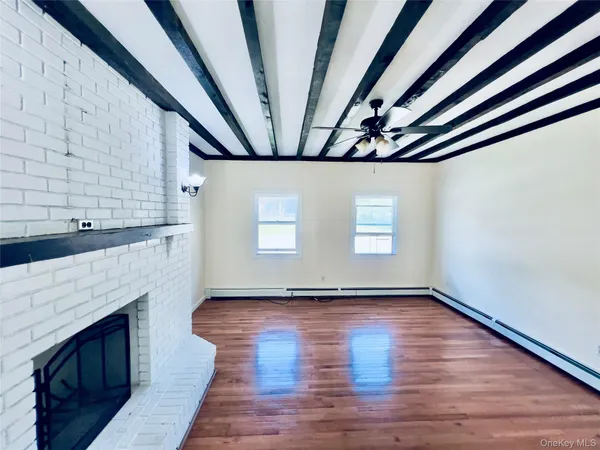 a view of an empty room with wooden floor and a fireplace