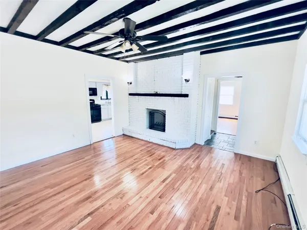 a view of an empty room with wooden floor and a ceiling fan