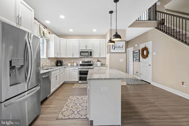 a kitchen with stainless steel appliances granite countertop a refrigerator a stove and a wooden floors