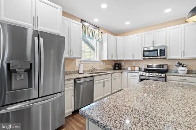 a kitchen with stainless steel appliances granite countertop a sink a stove and a wooden floor