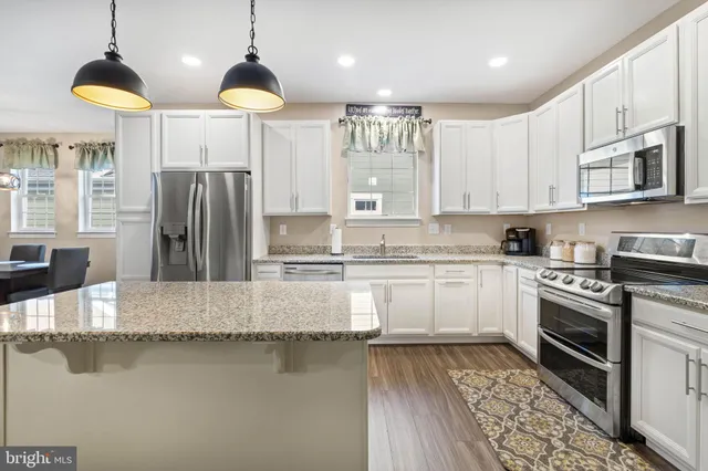 a kitchen with stainless steel appliances granite countertop a sink a stove and a wooden floor