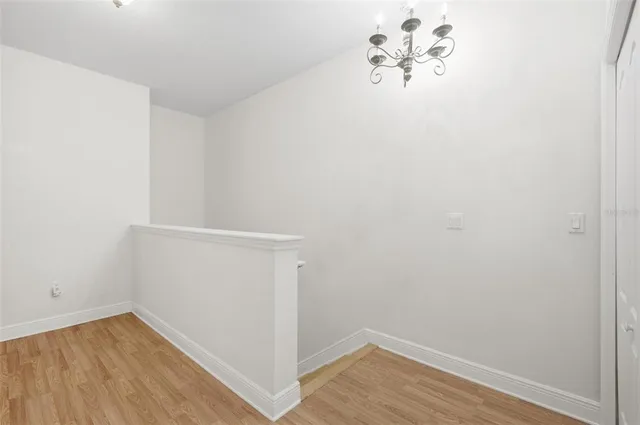 an empty room with wooden floor chandelier fan and closet area