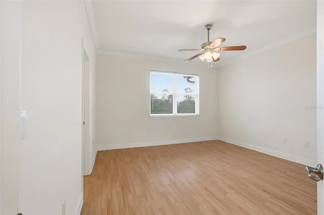 an empty room with wooden floor and ceiling fan
