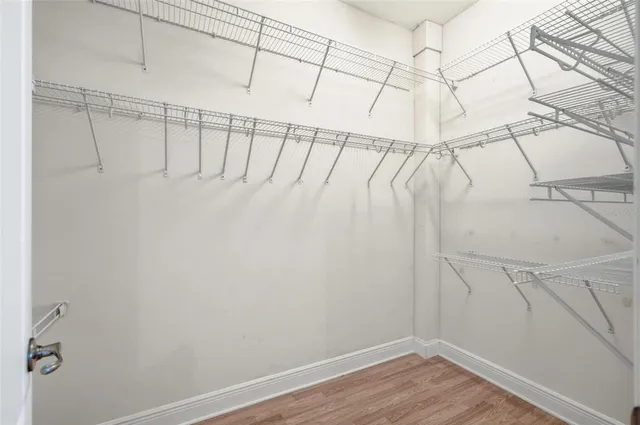 an empty room with wooden floor chandelier fan and closet area