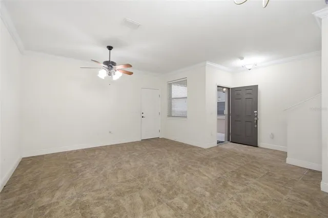 a view of an empty room with chandelier fan