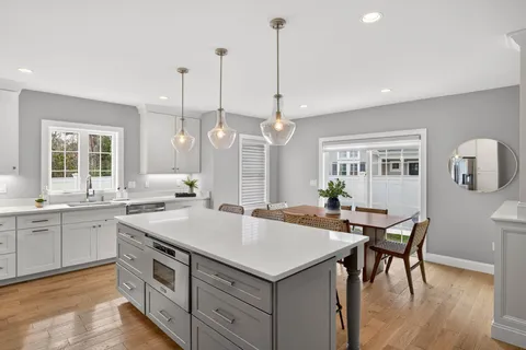 a open kitchen with stainless steel appliances granite countertop a stove a sink a dining table and chairs with wooden floor