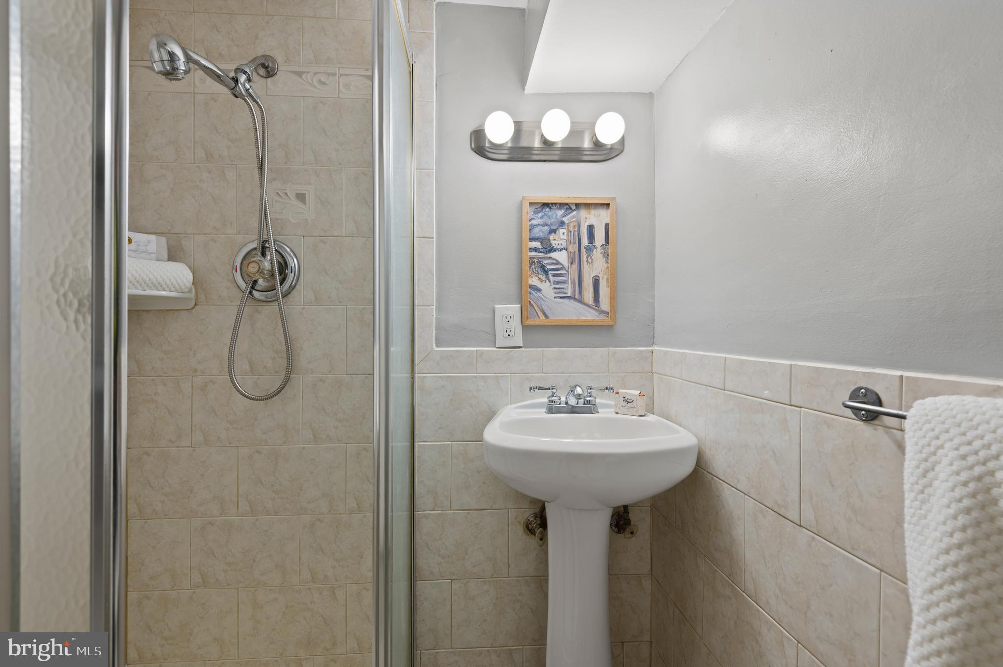 1236 Sargeant Street Baltimore, MD 21223 - Photo 18 of 19 a bathroom with a sink a mirror a shower and vanity