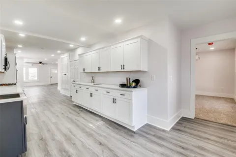a large white kitchen with white cabinets and wooden floor