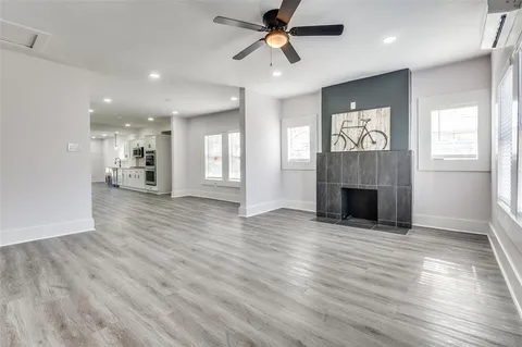 an empty room with wooden floor fireplace and windows