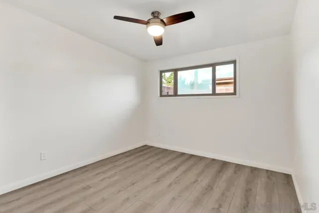 an empty room with a window and ceiling fan