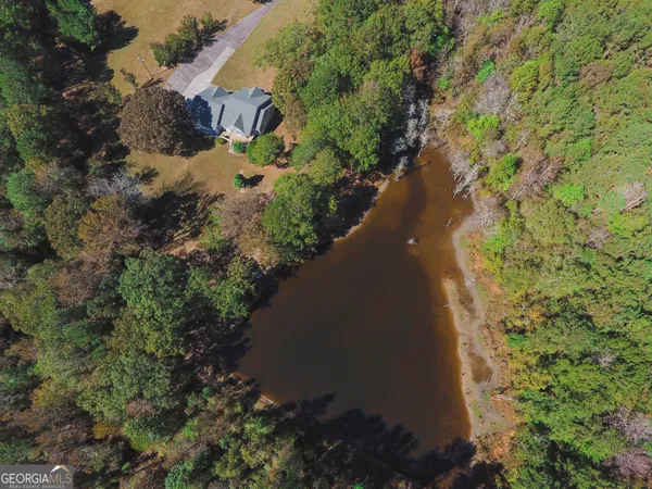 an aerial view of a house with a yard and trees all around