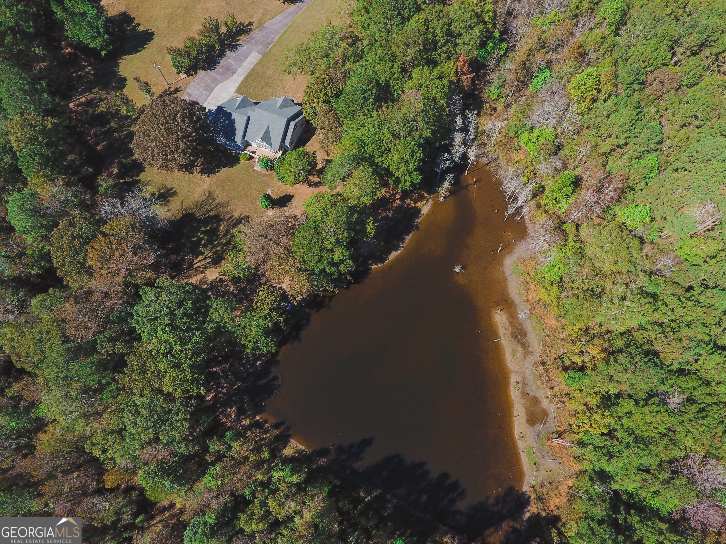 an aerial view of a house with a yard and trees all around
