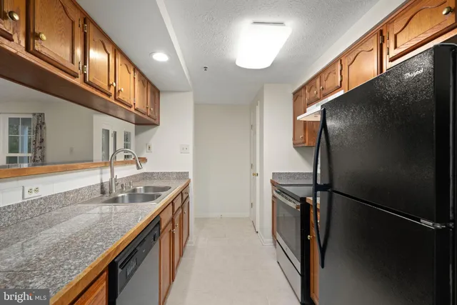 a kitchen with stainless steel appliances granite countertop a refrigerator a sink and a stove