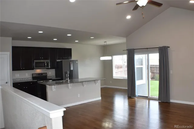 a large kitchen with stainless steel appliances a large counter top a stove and a refrigerator