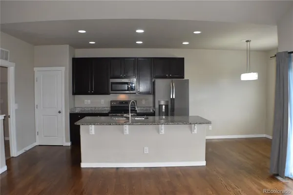 a kitchen with kitchen island stainless steel appliances a sink a stove a microwave and cabinets