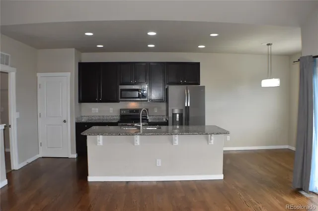 a kitchen with kitchen island stainless steel appliances a sink a stove a microwave and cabinets