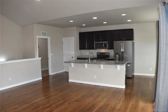 a view of kitchen with stainless steel appliances granite countertop a refrigerator and a stove top oven