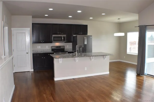a large kitchen with stainless steel appliances granite countertop a large counter top and wooden floors