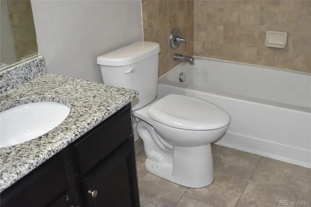 a bathroom with a granite countertop sink and a toilet