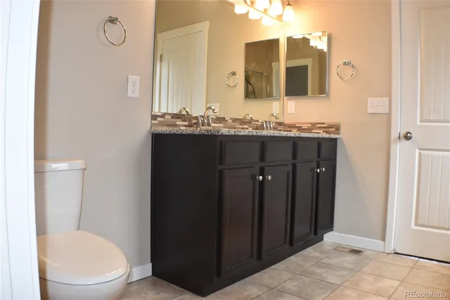 a bathroom with a granite countertop sink toilet and mirror