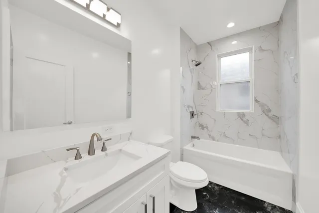 a bathroom with a bathtub shower sink vanity mirror and toilet
