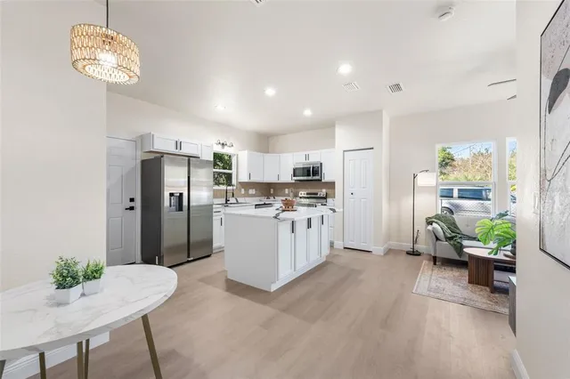 a kitchen with stainless steel appliances kitchen island a refrigerator and a view of living room