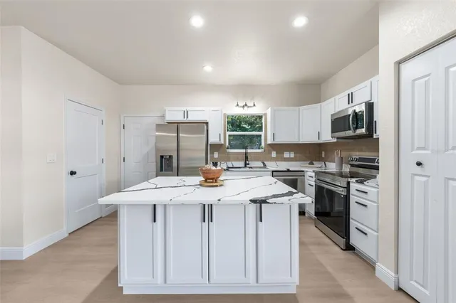 a kitchen with stainless steel appliances a sink a stove a refrigerator cabinets and a dining table