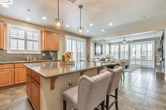 a kitchen with kitchen island granite countertop a table chairs refrigerator and cabinets