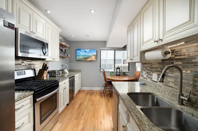 a kitchen with stainless steel appliances a sink a stove top oven a counter space and cabinets
