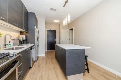 a kitchen with kitchen island a counter top space a sink stainless steel appliances and cabinets